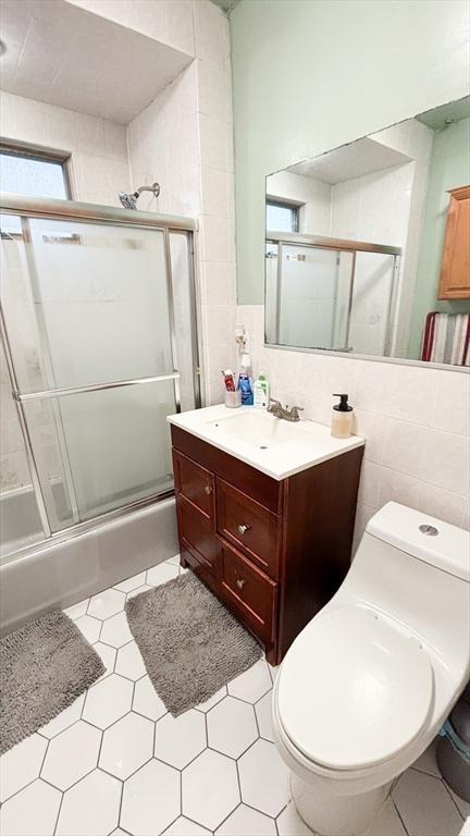 bathroom featuring vanity, toilet, and tile walls