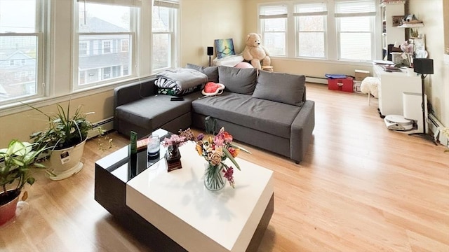living room featuring a baseboard radiator, a healthy amount of sunlight, light wood finished floors, and baseboard heating