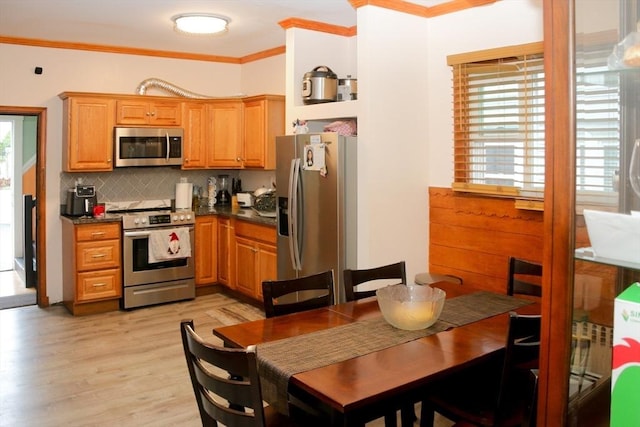 kitchen featuring tasteful backsplash, crown molding, appliances with stainless steel finishes, dark countertops, and light wood-type flooring