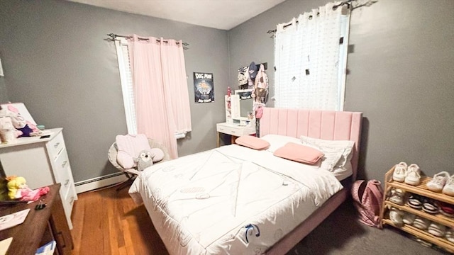 bedroom featuring wood finished floors and a baseboard radiator