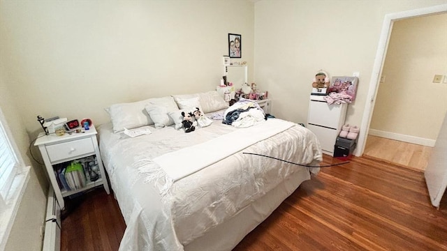 bedroom featuring baseboard heating and wood finished floors