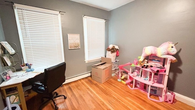 office with light wood-type flooring, a baseboard heating unit, and baseboards