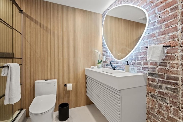 bathroom featuring vanity, toilet, a baseboard heating unit, and brick wall