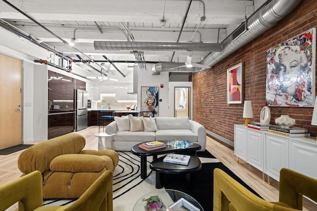 living room featuring brick wall and light hardwood / wood-style flooring