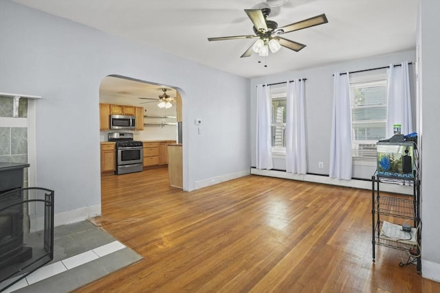 40 By St, Lowell, MA 01850 - unfurnished living room with arched walkways, a ceiling fan, light wood-style flooring, and baseboards
