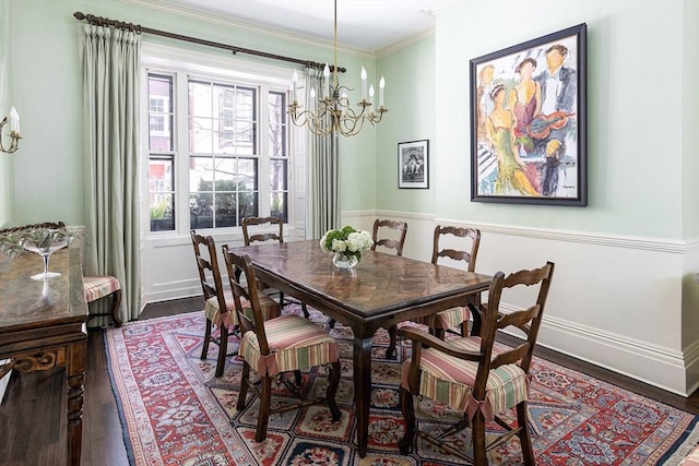 dining area featuring crown molding, an inviting chandelier, and wood finished floors