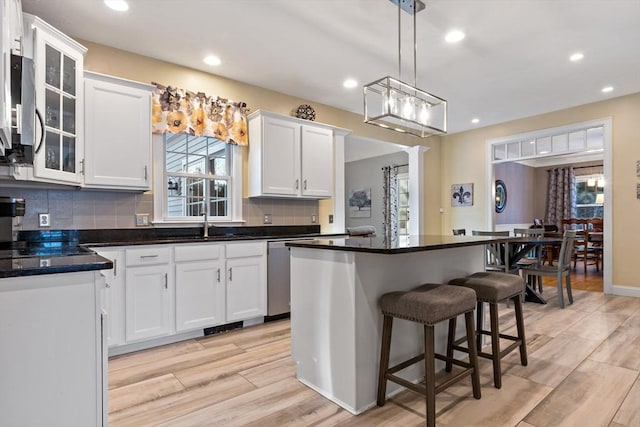 kitchen with tasteful backsplash, a kitchen bar, white cabinetry, and a sink