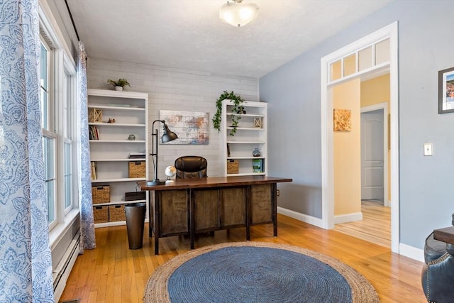 home office with light wood-type flooring, a baseboard radiator, and baseboards