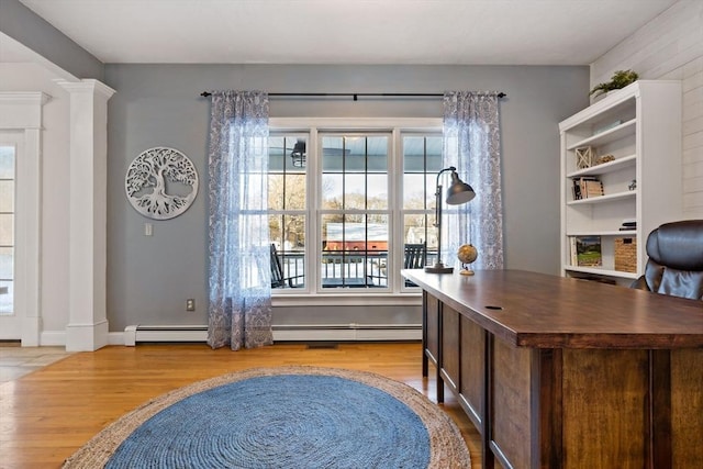 office area featuring decorative columns, baseboards, baseboard heating, and wood finished floors