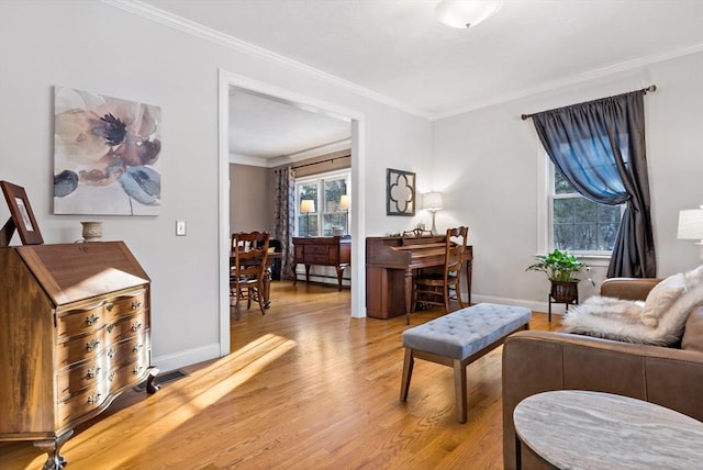 living area with visible vents, light wood-style flooring, ornamental molding, a baseboard heating unit, and baseboards