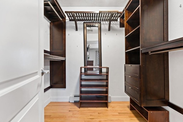 spacious closet featuring light wood-style floors and a baseboard radiator