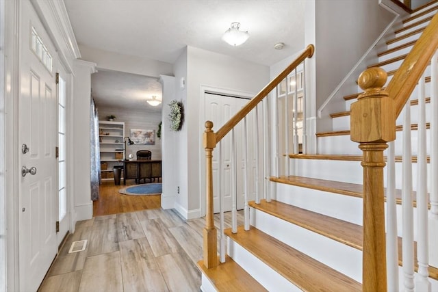 foyer with visible vents, stairs, baseboards, and wood finished floors