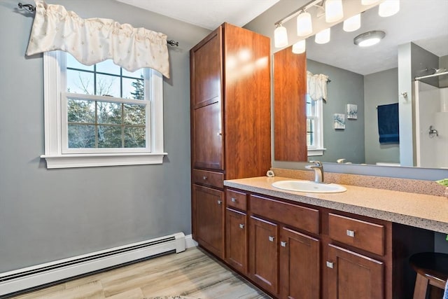 bathroom with a shower, baseboard heating, wood finished floors, and vanity