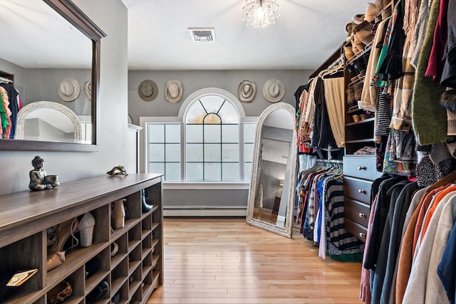 walk in closet featuring a baseboard radiator, visible vents, an inviting chandelier, and wood finished floors