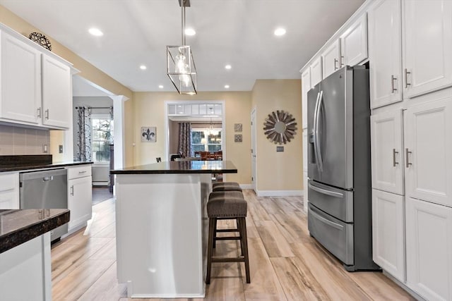 kitchen featuring white cabinets, appliances with stainless steel finishes, a breakfast bar, and backsplash