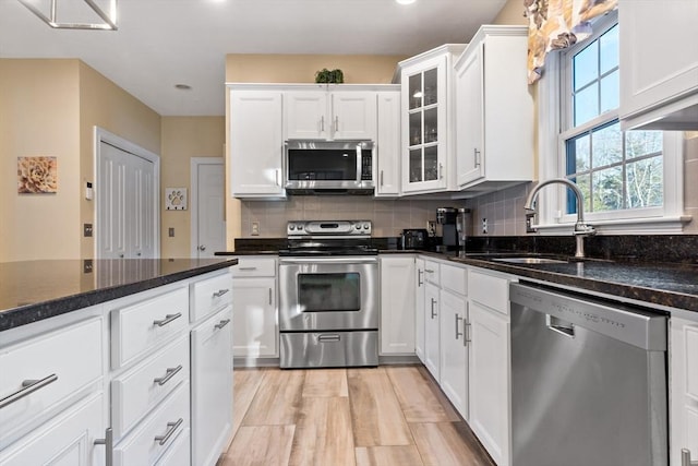 kitchen featuring stainless steel appliances, tasteful backsplash, a sink, and white cabinetry