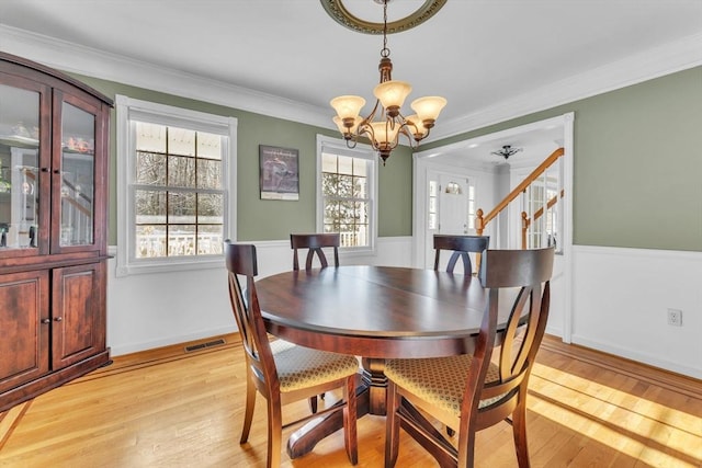 dining space featuring a wainscoted wall, light wood-style flooring, and crown molding