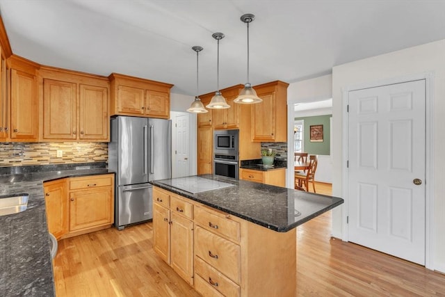 kitchen featuring tasteful backsplash, appliances with stainless steel finishes, decorative light fixtures, light wood-type flooring, and a kitchen island