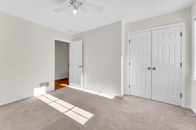 unfurnished bedroom featuring visible vents, a closet, light carpet, and ceiling fan