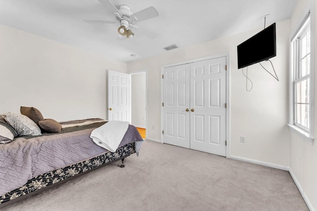 bedroom featuring light colored carpet, visible vents, a ceiling fan, baseboards, and a closet