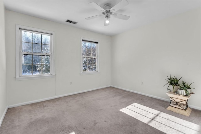 spare room featuring plenty of natural light, visible vents, light carpet, and baseboards