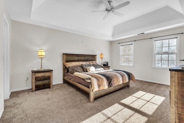 carpeted bedroom with baseboards, ceiling fan, visible vents, and a tray ceiling