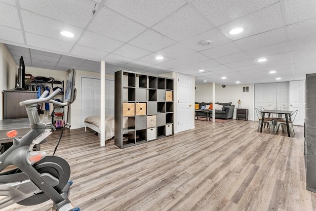 workout room featuring light wood-type flooring, recessed lighting, and a drop ceiling