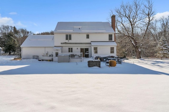 snow covered back of property with a chimney