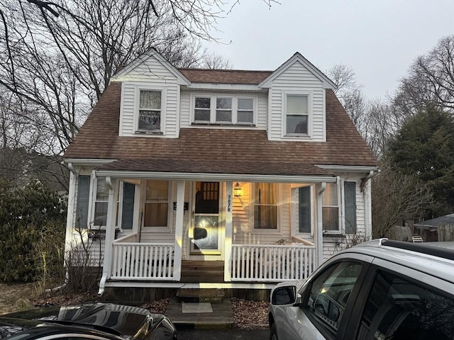 view of front of property with a porch, central air condition unit, and a shingled roof