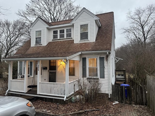 view of front of house featuring covered porch, roof with shingles, and fence