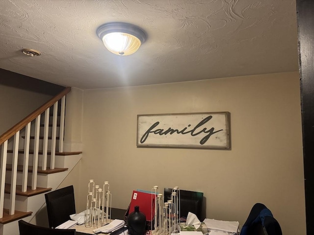 unfurnished dining area with a textured ceiling and stairs