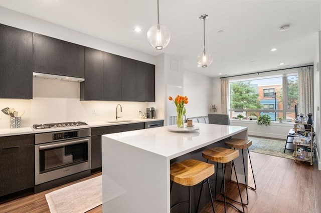 kitchen featuring appliances with stainless steel finishes, a breakfast bar, light countertops, and a sink