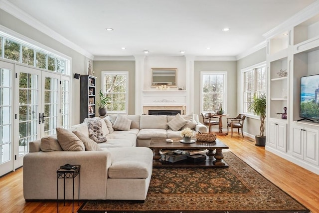 living room featuring crown molding, french doors, built in shelves, and light wood-type flooring