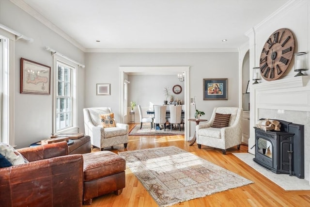 living room with wood-type flooring, a wood stove, and crown molding