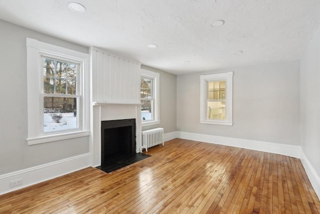 unfurnished living room with radiator heating unit and light hardwood / wood-style floors