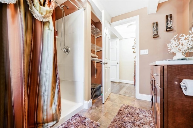bathroom featuring vanity, a shower stall, tile patterned flooring, and baseboards