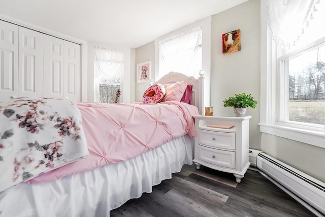 bedroom featuring a baseboard radiator, a closet, dark wood-style flooring, and multiple windows