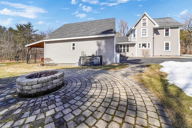 rear view of property with an outdoor fire pit, a patio, and a shingled roof