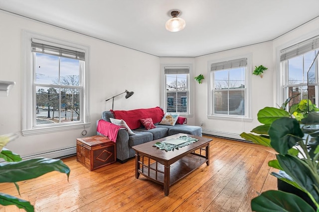 living room with a healthy amount of sunlight, light wood-type flooring, and a baseboard heating unit