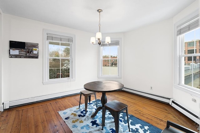 dining space with a healthy amount of sunlight, a baseboard radiator, wood-type flooring, and a notable chandelier