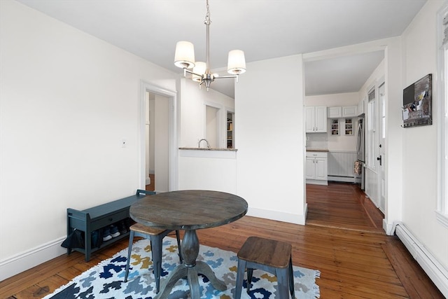 dining space with an inviting chandelier, dark wood-type flooring, and a baseboard radiator