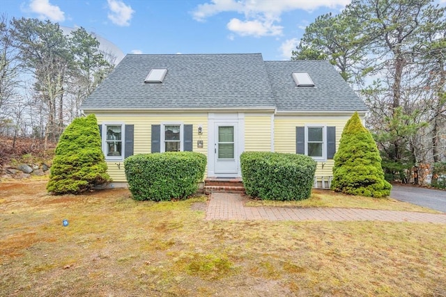 cape cod home with a front lawn and roof with shingles