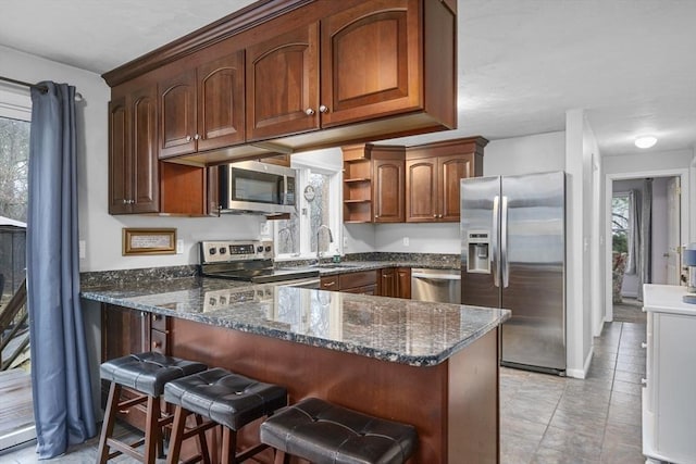 kitchen featuring a sink, open shelves, appliances with stainless steel finishes, a peninsula, and dark stone counters