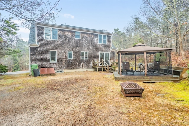 rear view of property with an outdoor fire pit, a gazebo, and a deck
