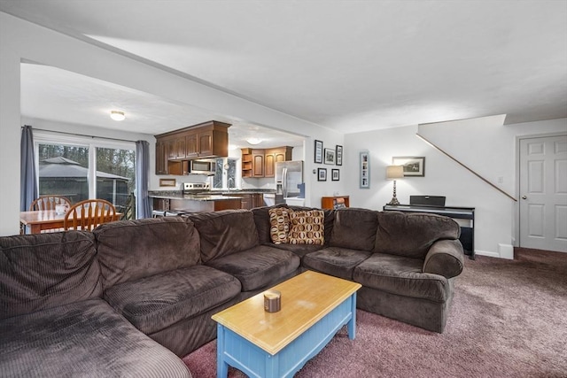 carpeted living area with baseboards and a sink