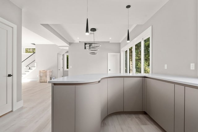 kitchen with a notable chandelier, hanging light fixtures, light hardwood / wood-style floors, and gray cabinetry