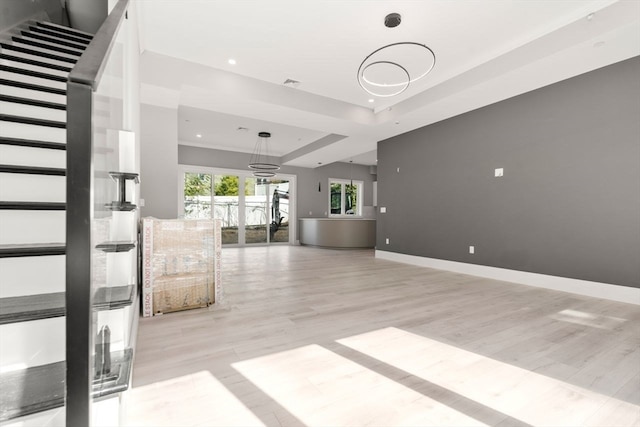 unfurnished living room featuring light hardwood / wood-style flooring and a raised ceiling