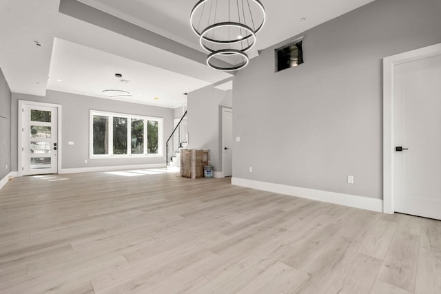 unfurnished living room with light wood-type flooring and an inviting chandelier