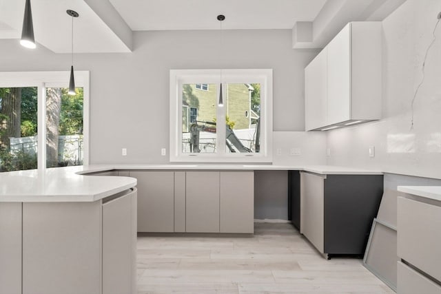 kitchen featuring pendant lighting, light wood-type flooring, and kitchen peninsula