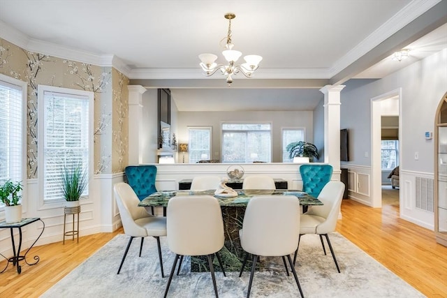 living area with hardwood / wood-style floors, decorative columns, an inviting chandelier, and crown molding